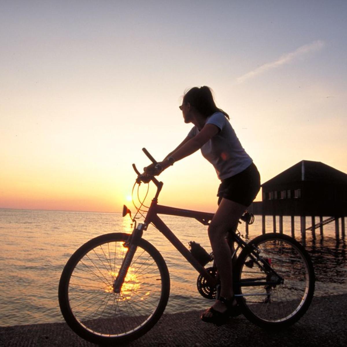 Radfahrerin am Bodensee beim Sonnenuntergang